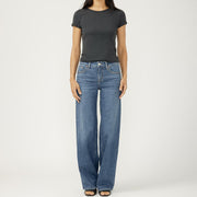 Woman wearing a black t-shirt and blue jeans on a white background