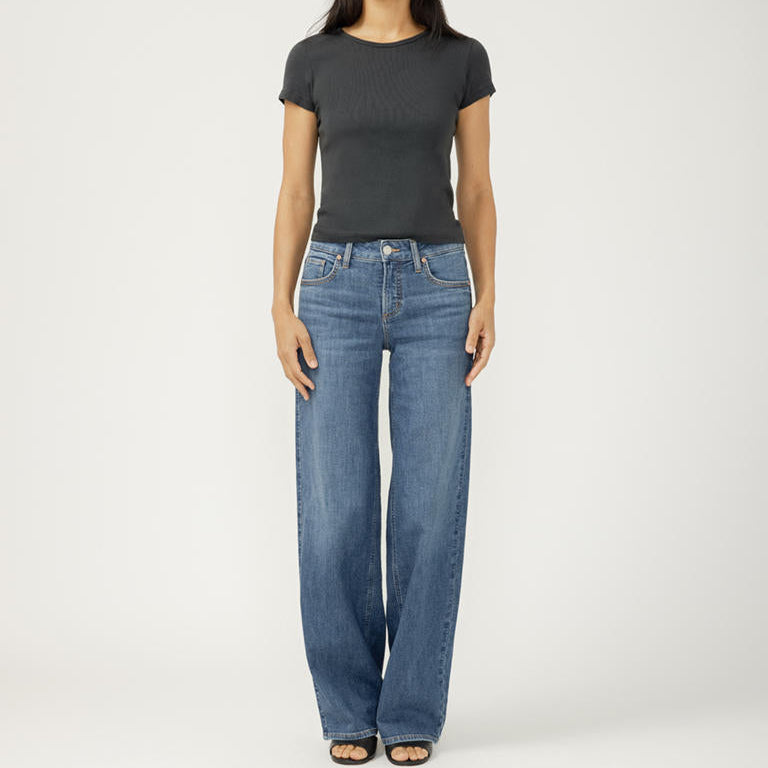 Woman wearing a black t-shirt and blue jeans on a white background