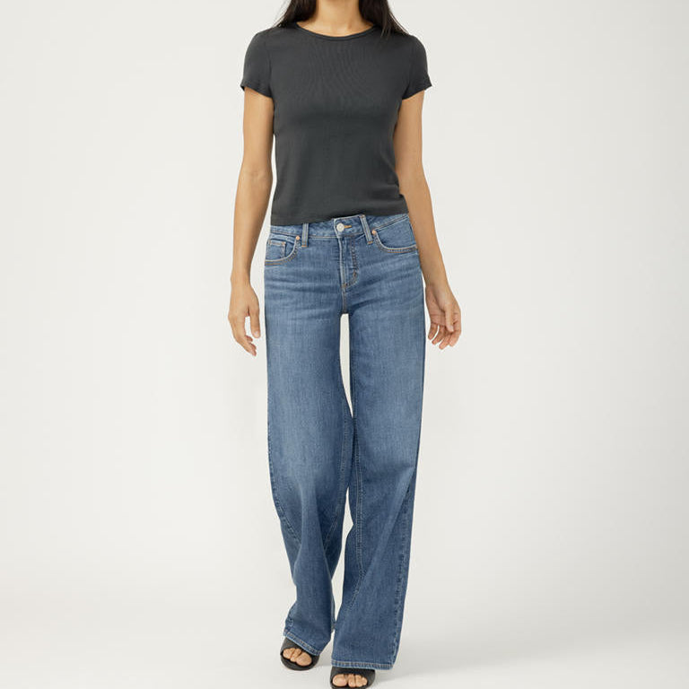 Person wearing a black t-shirt and blue jeans on a white background